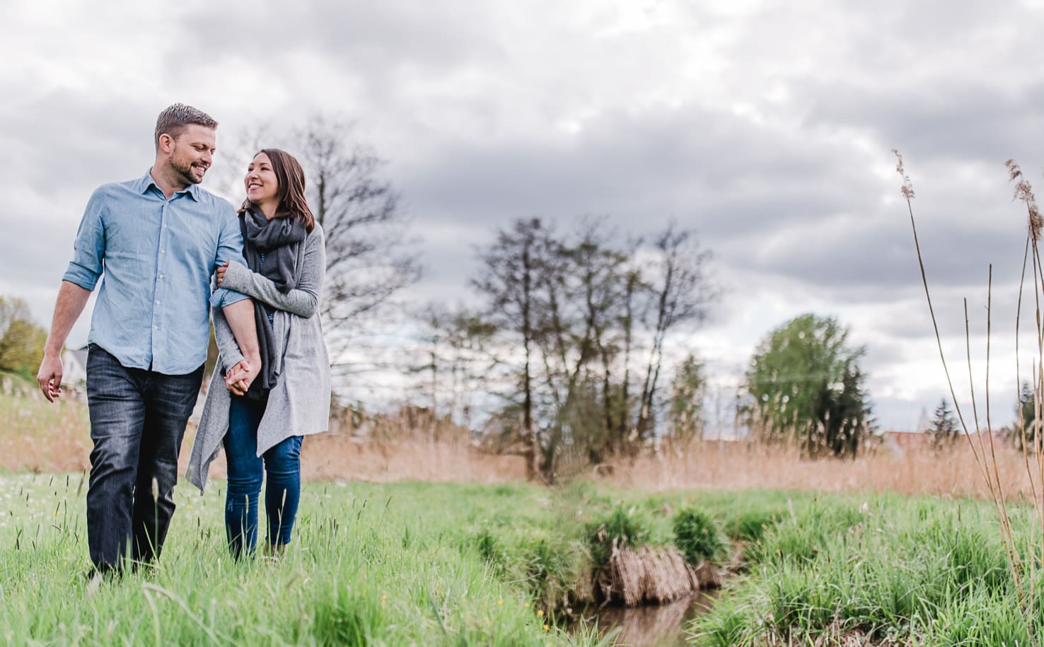 Engagementshooting auf dem Land, Pärchenfotos im Wald, Paarfotos bei Wolken und Wind, Paarfotos von Jung und Wild design bei und um München