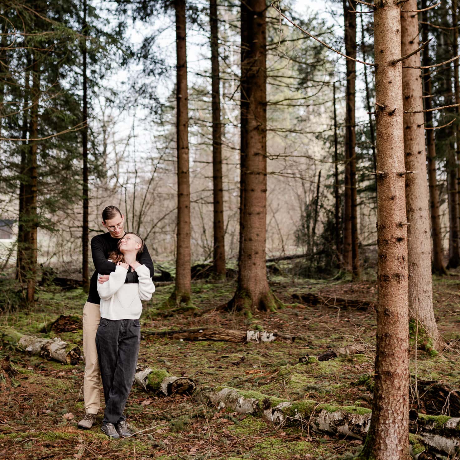 Ein Mann umarmt eine Frau im Wald.