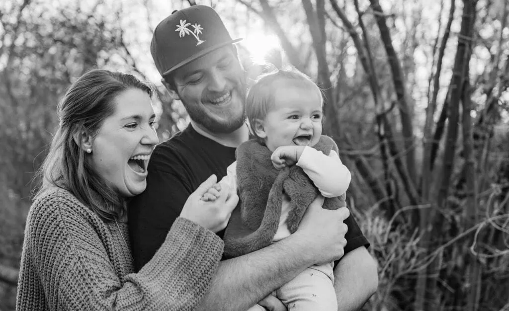 Eine Familie lacht und spielt gemeinsam draußen.