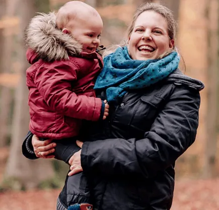 Eine Frau hält ein lächelndes Kind im Arm.