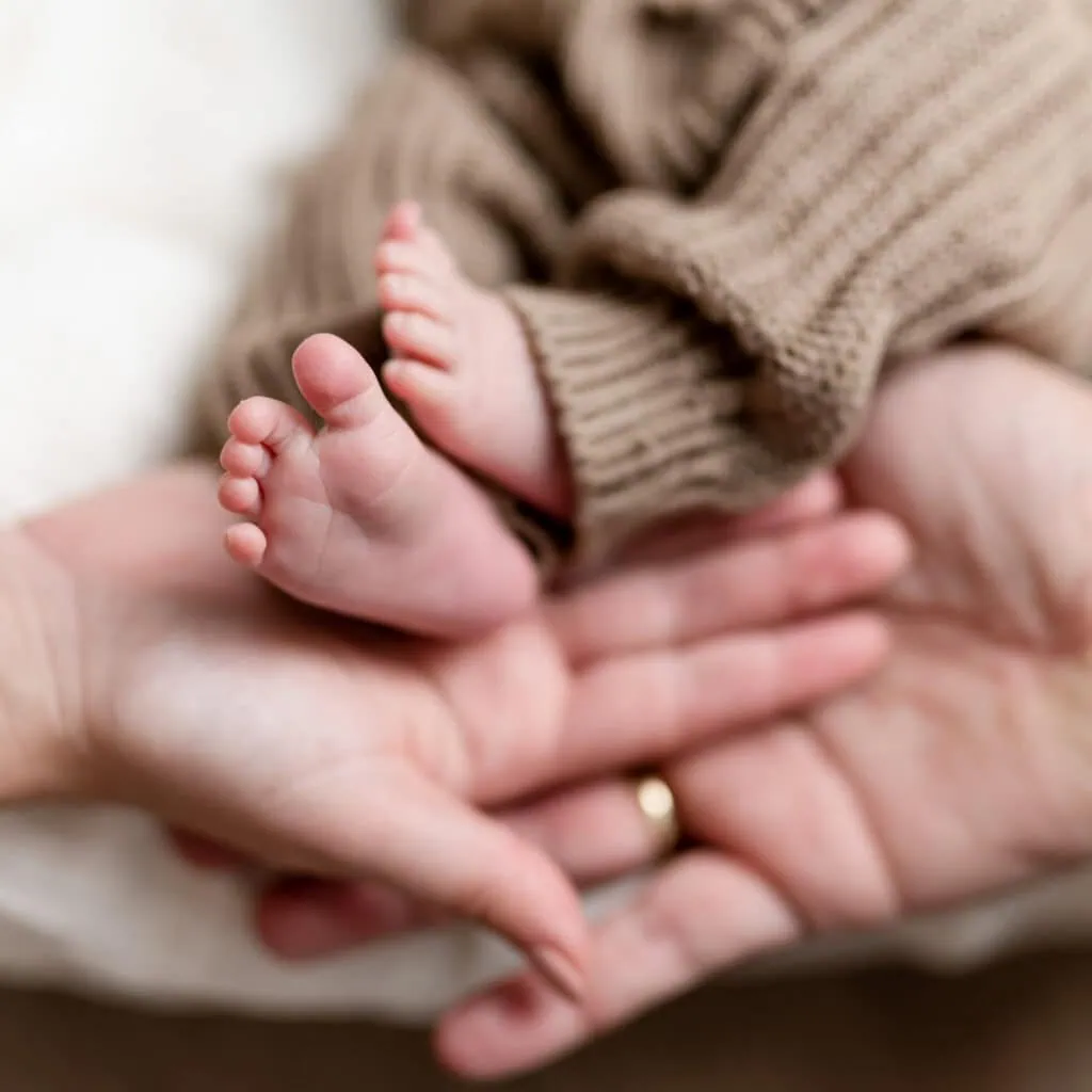 Das Bild zeigt die kleinen Füße eines Babys, die behutsam in den Händen einer erwachsenen Person liegen.