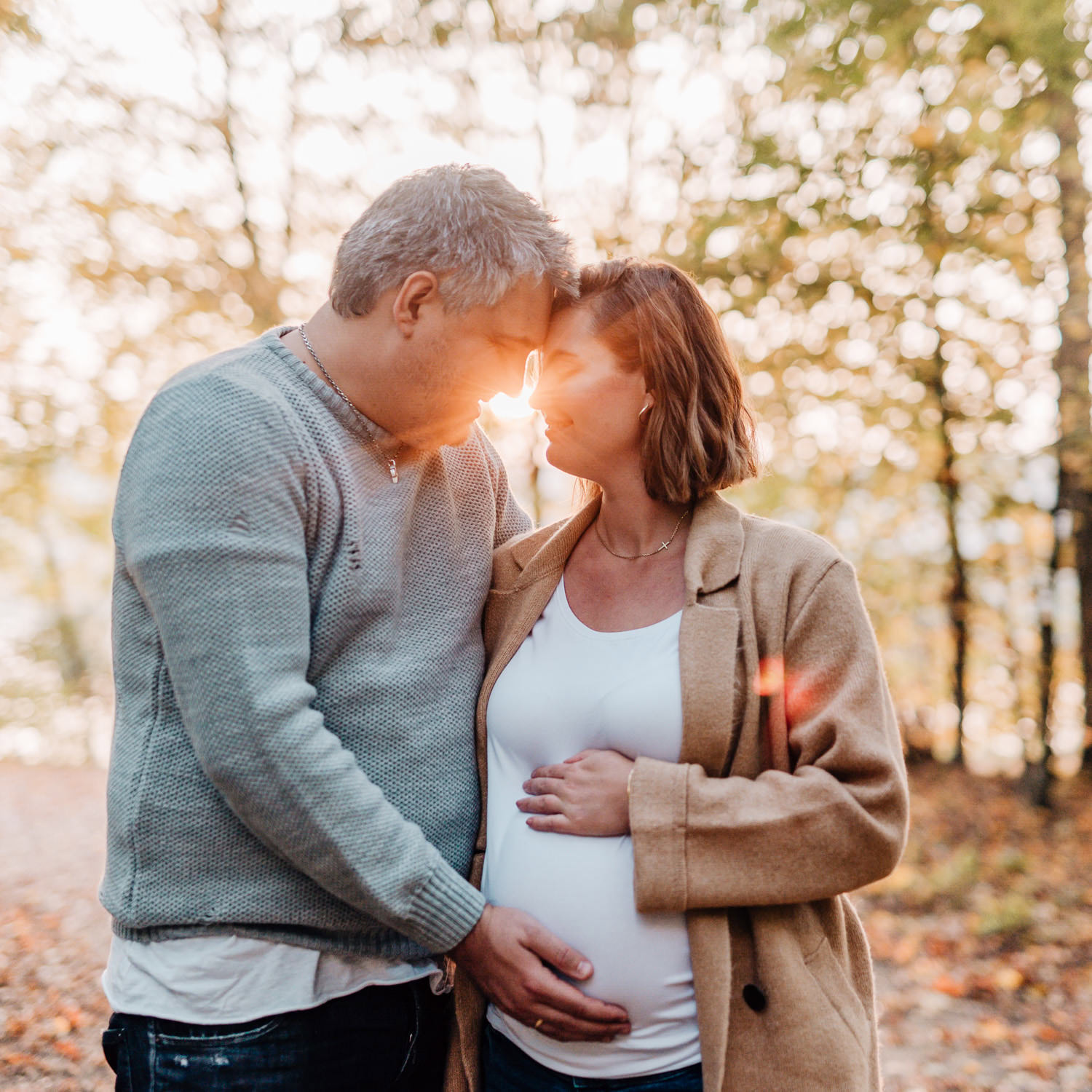 Das Bild zeigt ein Paar, das sich liebevoll an der Stirn berührt, die Frau ist schwanger.