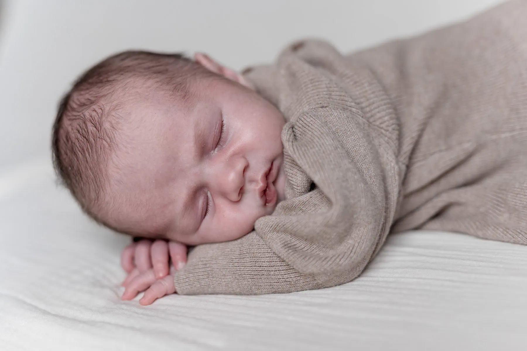 Ein schlafendes Baby eingewickelt in eine Decke.