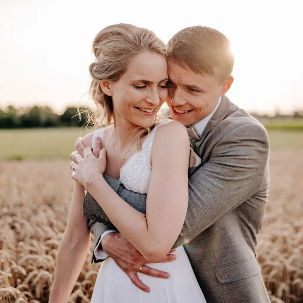 Das ist ein Bild von zwei Menschen, die sich umarmen und glücklich wirken, möglicherweise ein Hochzeitspaar auf einem Feld.