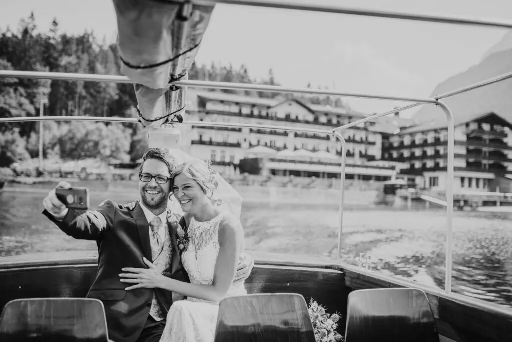 Ein glückliches Paar in Hochzeitskleidung macht ein Selfie auf einem Boot.