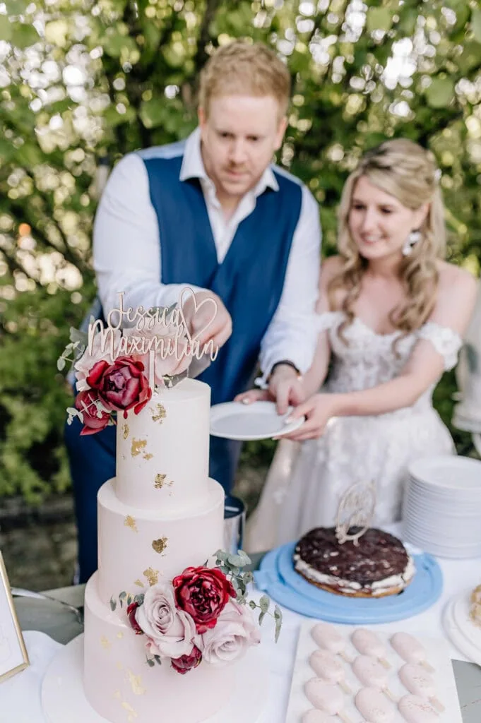 Zwei Personen schneiden zusammen eine Hochzeitstorte an.