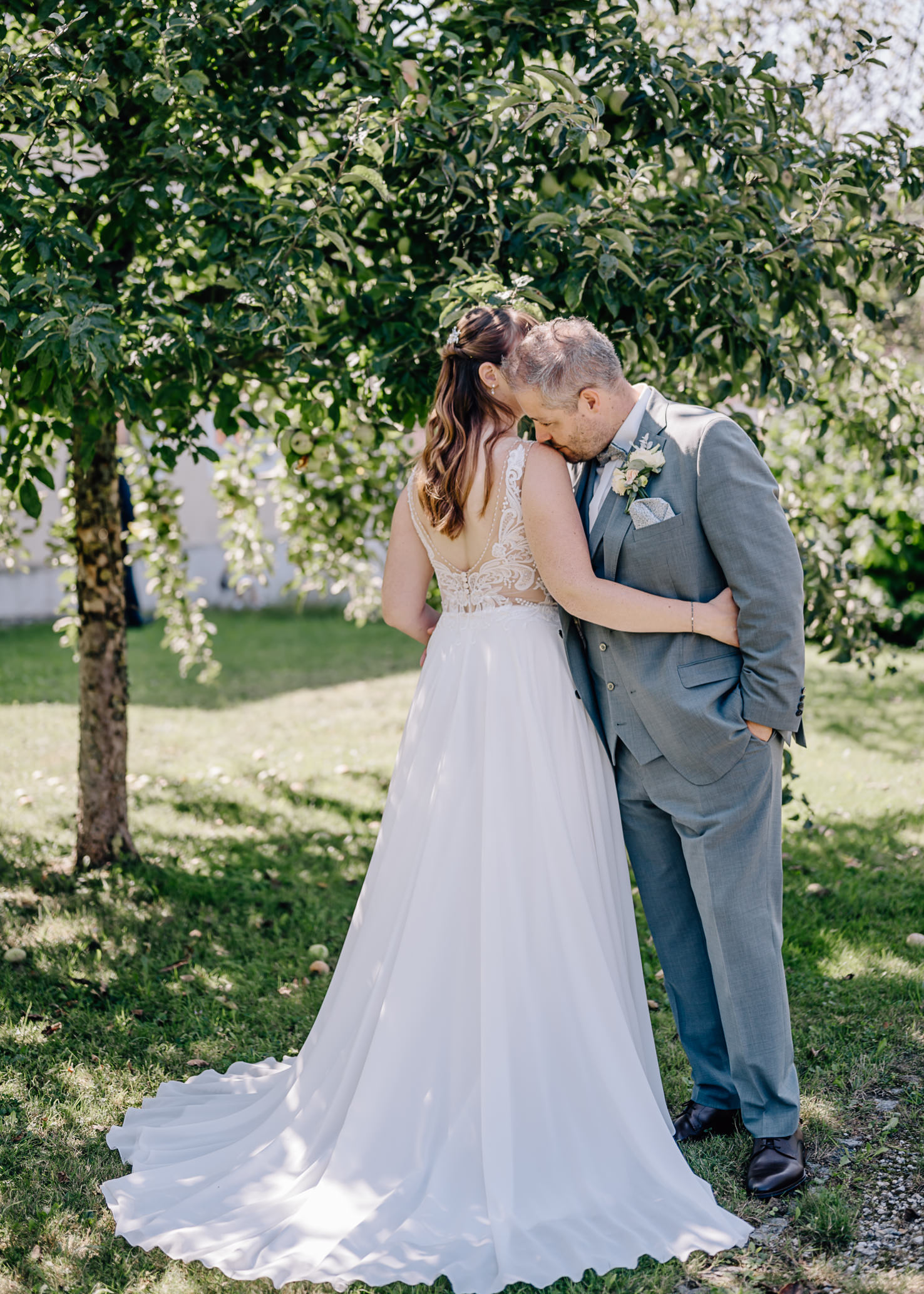 Das Bild zeigt eine Hochzeitspaar, das sich zärtlich unter einem Baum küsst.