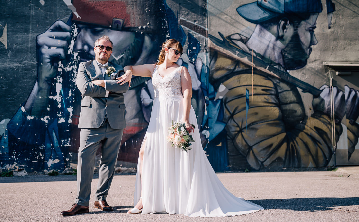 Ein Brautpaar posiert vor einem großen Wandgemälde.