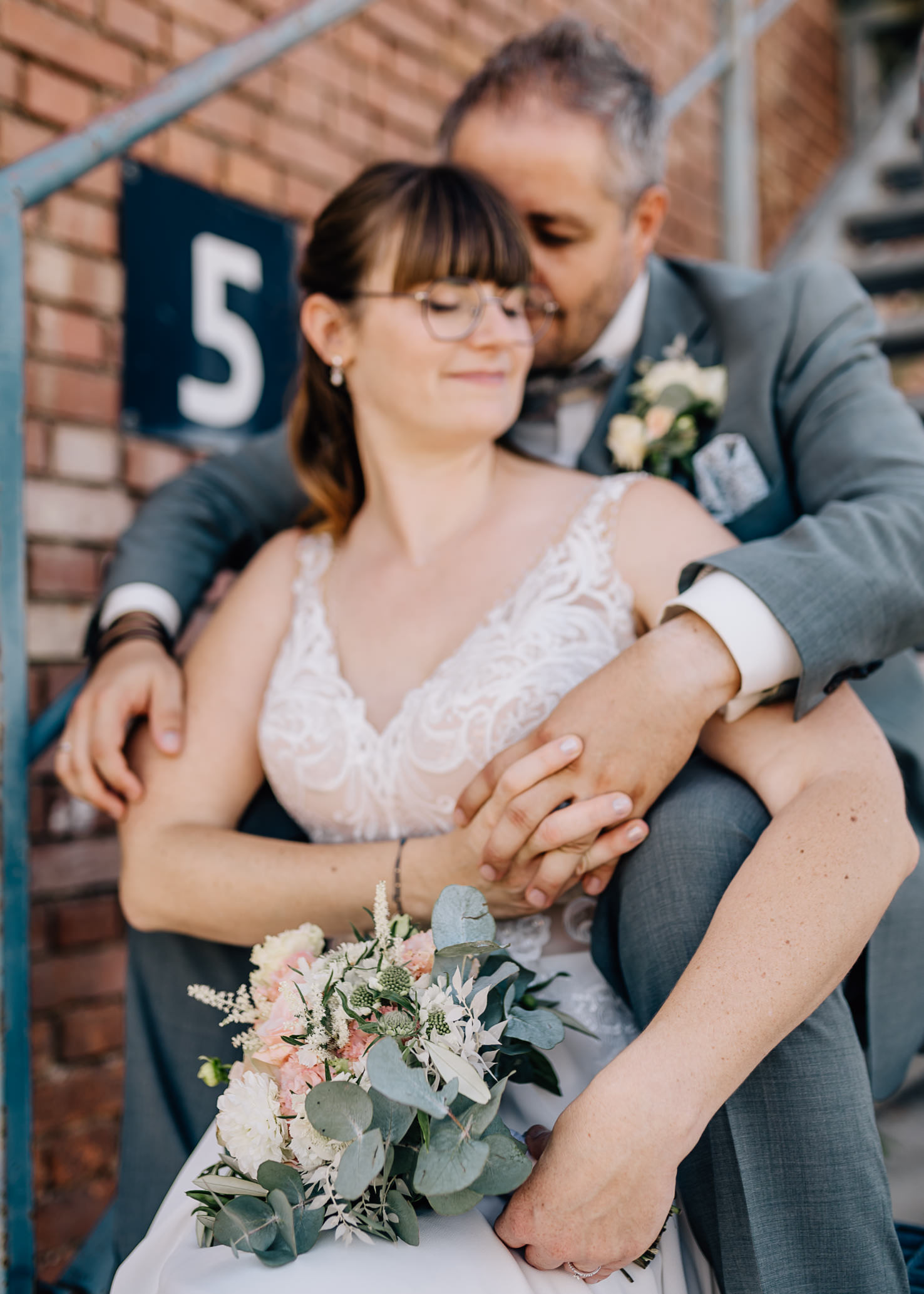 Das Bild zeigt ein vermutlich frisch verheiratetes Paar in Hochzeitskleidung, das Zärtlichkeiten austauscht.