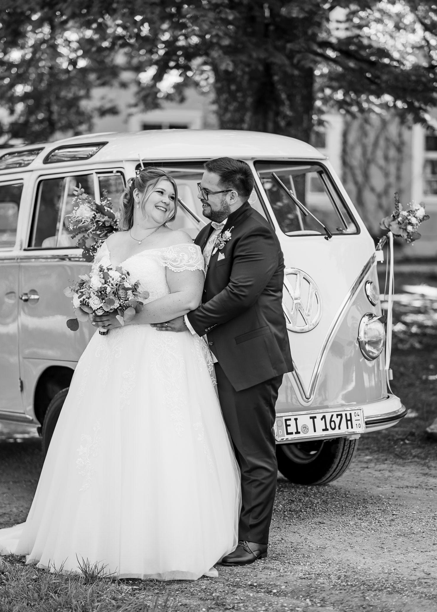 In diesem romantischen Hochzeitsbild von Mica Zeitz strahlen das Brautpaar und die liebevolle Atmosphäre perfekte Harmonie aus, während sie vor einem nostalgischen VW-Bus posieren. Die emotionale Verbindung und die stilvollen Details der Hochzeit werden eindrucksvoll festgehalten, was dieses Foto zu einem zeitlosen Erinnerungsstück macht.