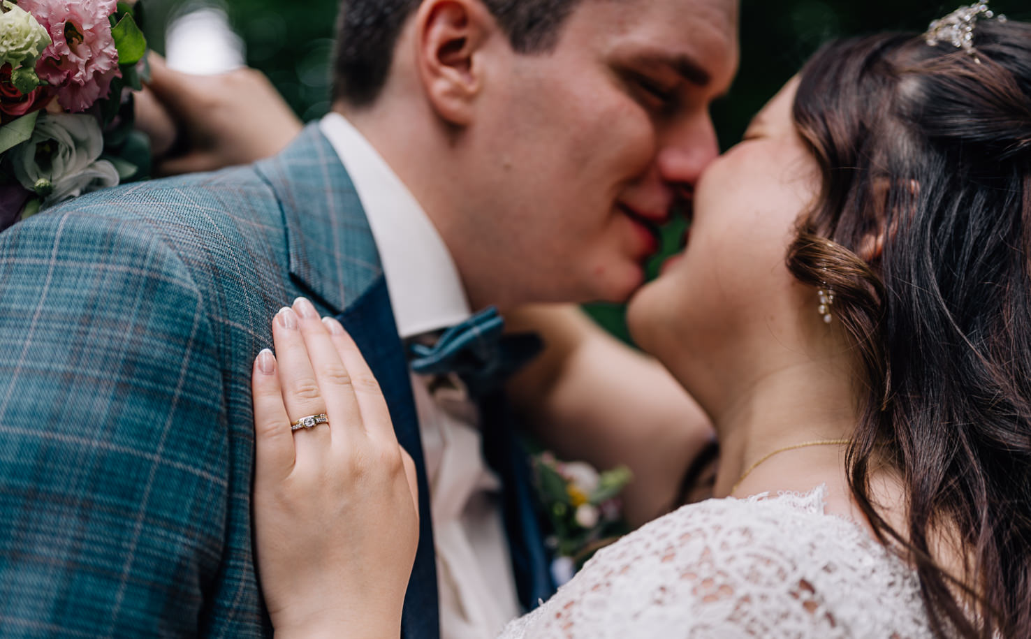 Das romantische Bild von Mica Zeitz fängt den innigen Moment eines Paares beim Küssen ein, geprägt von Zärtlichkeit und Liebe. Die perfekte Kombination aus einem eleganten Hochzeitsoutfit und einem bunten Blumenarrangement macht diese Aufnahme zu einem unvergesslichen Hochzeitsfoto.