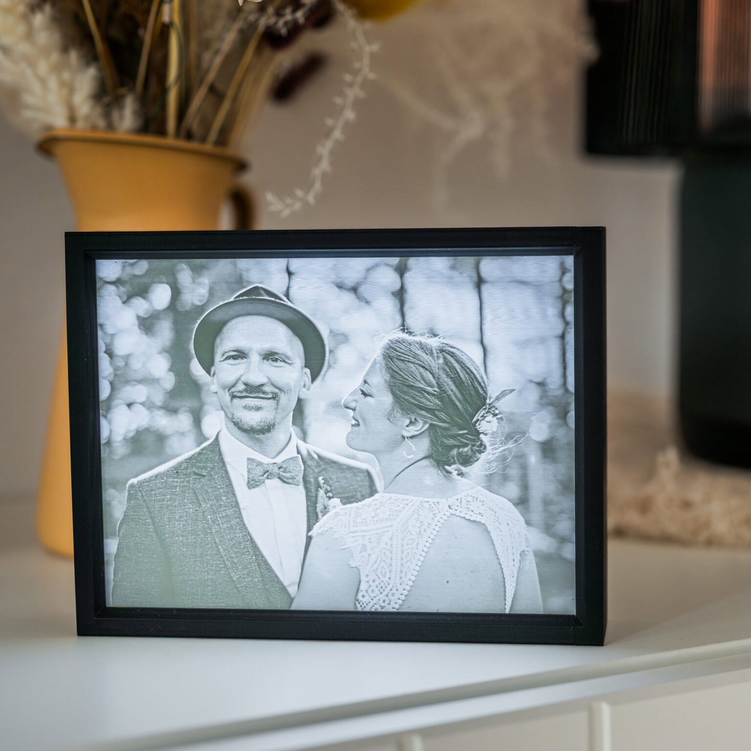 Dieses ausdrucksstarke Schwarz-Weiß-Foto, aufgenommen von der Fotografin Mica Zeitz, zeigt ein glückliches Brautpaar in einem romantischen Moment, umrahmt von natürlicher Schönheit im Hintergrund. Die zarten Details des Hochzeitskleides und der stilvolle Anzug verleihen dem Bild eine zeitlose Eleganz, perfekt für Hochzeitsfotografie-Liebhaber.