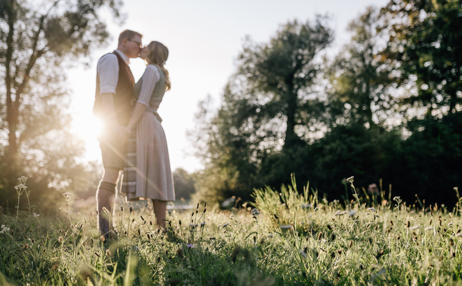 Dieses romantische Paar, das sich in einem malerischen, blühenden Feld küsst, fängt die zarte Atmosphäre der Zuneigung ein und wird eindrucksvoll von der talentierten Fotografin Mica Zeitz festgehalten. Die sanften Lichtverhältnisse und die natürliche Umgebung verleihen dem Bild eine traumhafte, nostalgische Note, perfekt für Hochzeits- und Paarfotografie.