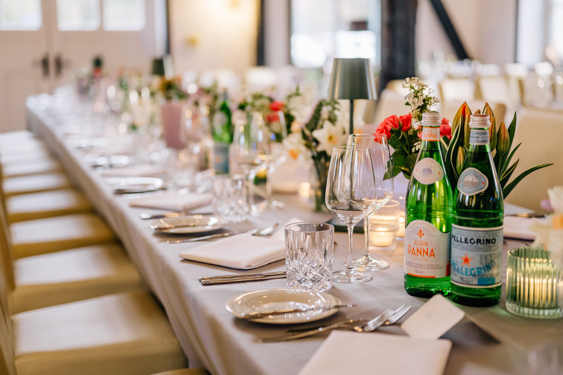 Das Bild zeigt eine festlich gedeckte Tafel in einer eleganten Hochzeitslocation, die für ihre ansprechende Atmosphäre bekannt ist. Die farbenfrohen Blumenarrangements und sorgfältig platzierten Details machen das Forsthaus Wörnbrunn zu einer empfohlenen Wahl für jeden besonderen Anlass, festgehalten von der Fotografin Mica Zeitz.