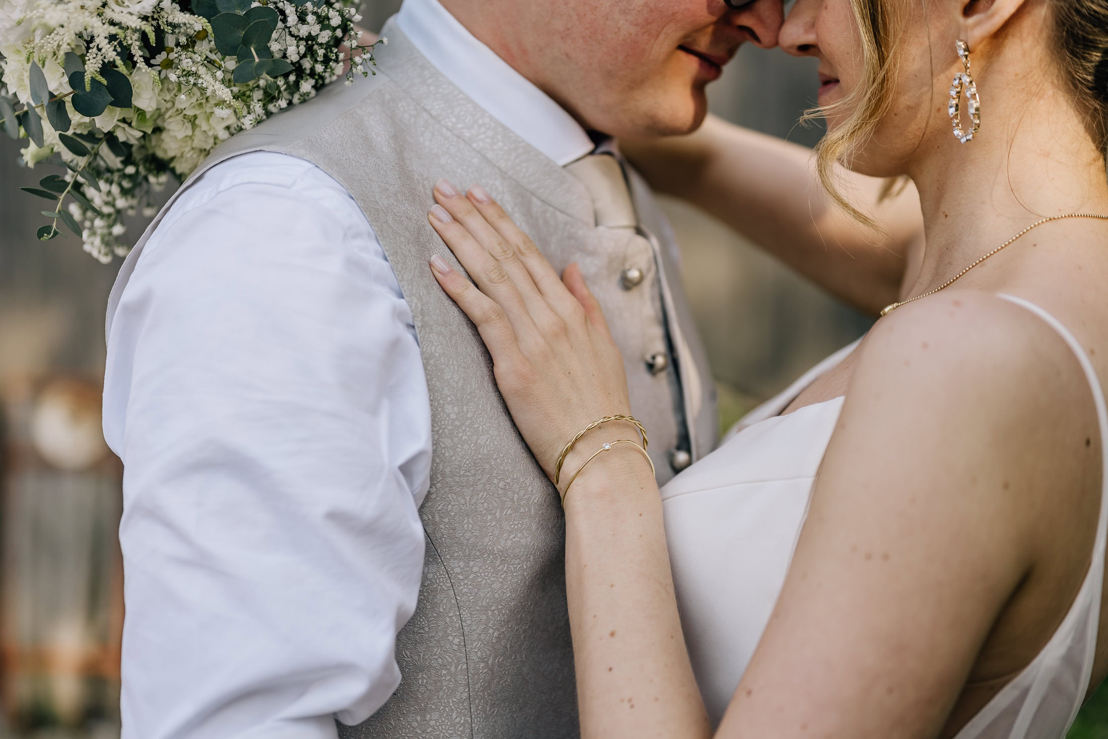 Das Bild zeigt ein romantisches Moment während einer Frühlingshochzeit mit einer Hochzeitsreportage, wo das Brautpaar in inniger Nähe zueinander steht. Die liebevolle Umarmung und der florale Brautstrauß im Hintergrund unterstreichen die besondere Atmosphäre der Hochzeit in Eder am Holz. Fotografin Mica Zeitz hat diesen zauberhaften Augenblick perfekt festgehalten.