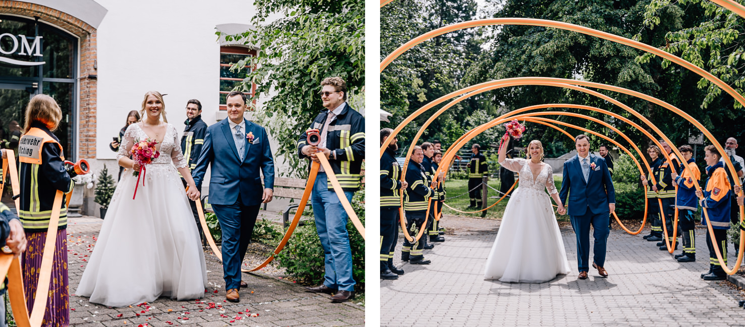Auf den Hochzeitsfotos von Mica Zeitz aus Olching stehen ein strahlendes Brautpaar im Mittelpunkt, das lächelnd unter einer bunten Ringekonstruktion geht. Die festliche Stimmung wird von Feuerwehrleuten und zahlreichen Blumenarrangements unterstrichen, die den bezaubernden Moment umrahmen.
